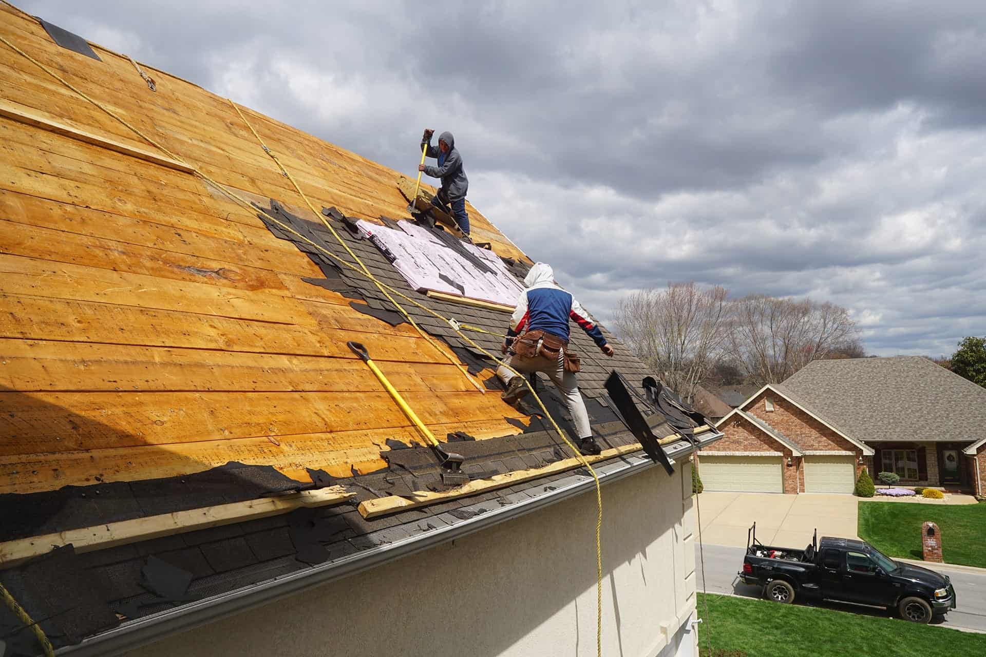 A construction worker wearing PPE installs electrical equipment on a roof.